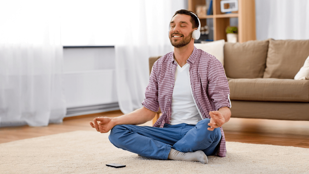 Mand, der laver MediYoga derhjemme med en session fra MediYoga Play-appen.