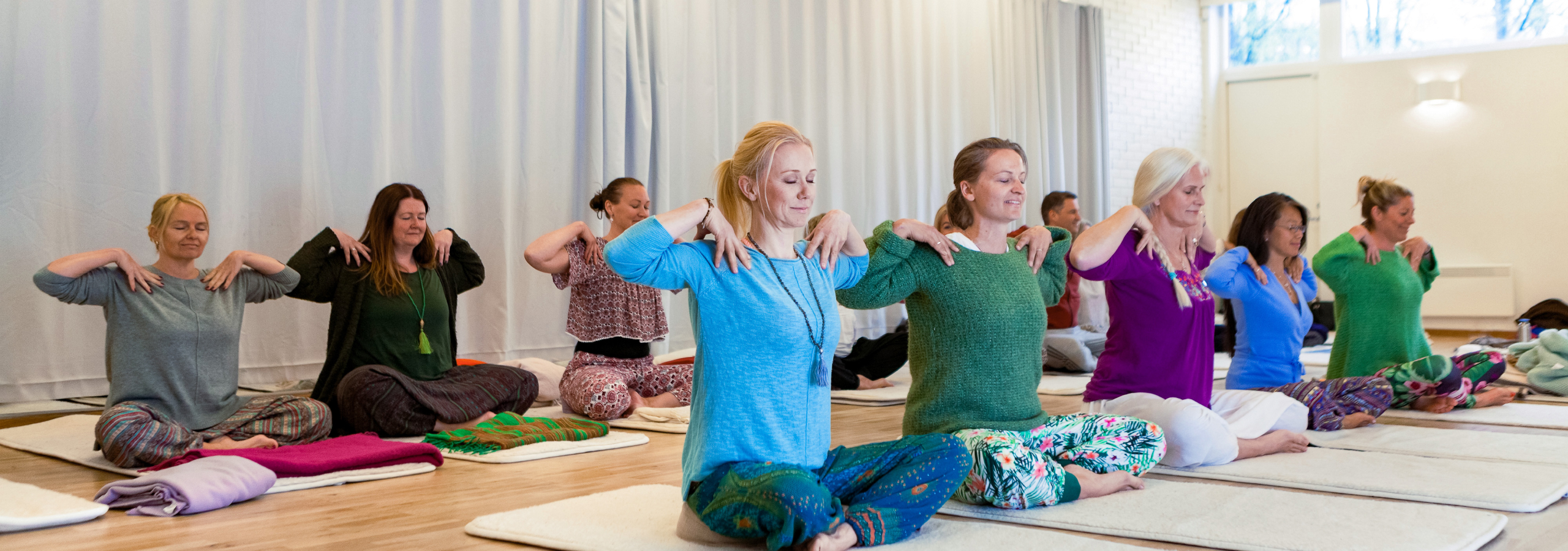 En gruppe deltagere, der dyrker MediYoga sammen i en guidet MediYoga-klasse.